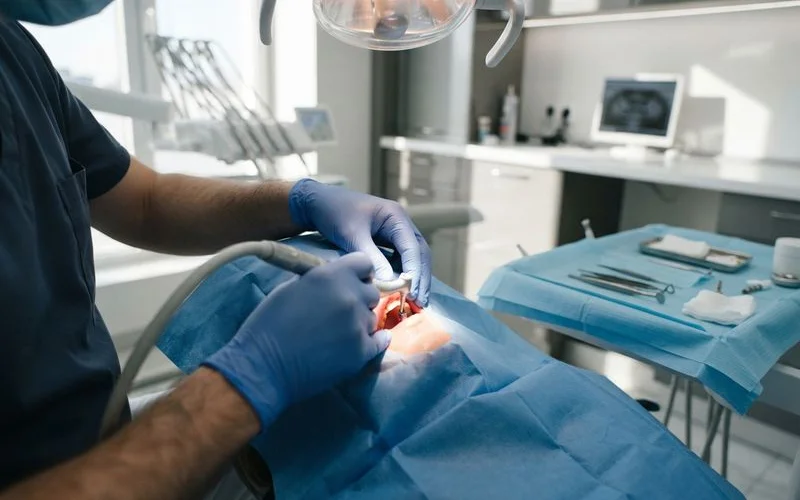 Oral surgeon and dental assistant working together during a dental implant placement procedure, surgical instruments arranged on a sterile tray